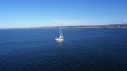 Sailboat sailing across the calm blue waters of monterey bay California by drone