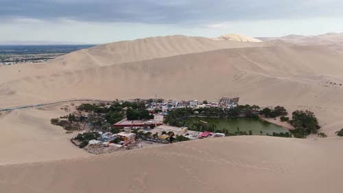 Vista aérea del oasis de Huacachina en Perú con dunas de arena y un lago sereno