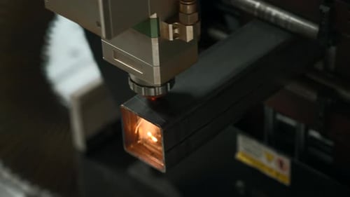 Laser cut head machine while cutting the sheet metal with the sparking light in factory