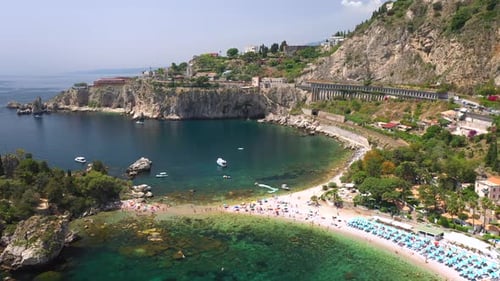 Drone shot of the Isola Bella coastline. Near Taormina, Sicily, southern Italy. With people on the b