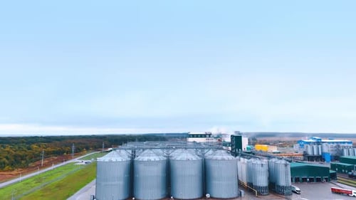 Modern grain silos elevator surrounded by agricultural fields.