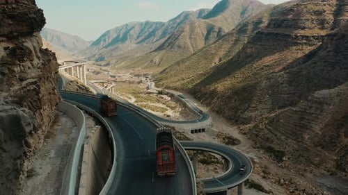 Luftaufnahme von Lastwagen, die entlang der CPEC-Straße am Waldrand fahren