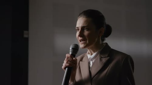 Woman Giving Speech With Microphone Wearing Business Suit