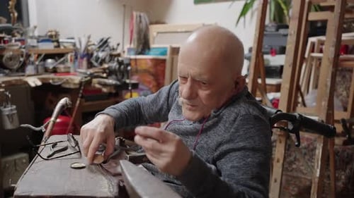 Senior Elderly Master Jeweler in Wheelchair Works in a Workshop