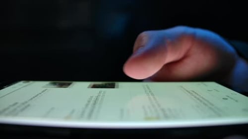Finger Scrolling Social Media Feed on Tablet at Night