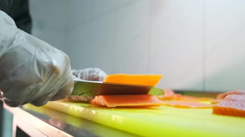 Gloved Hand Slicing Fresh Salmon with Knife