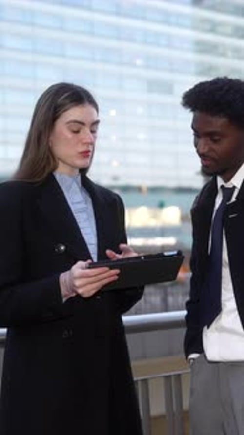 Business Colleagues Discussing Work on a Tablet Outside