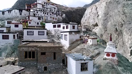 close up descriptive aerial view of an abandoned buddhist monastery over a rocky mountain. no humans