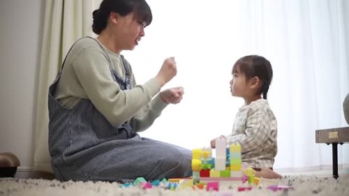 Happy Mother Playing Toy Blocks with Little Girl