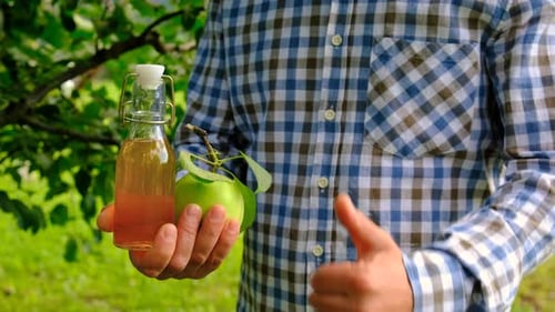 Man Holding Apple and Apple Cider in Orchard