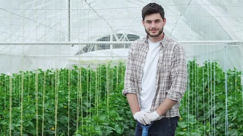 Young Adult Farmer in Greenhouse with Shovel