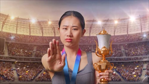 Gros plan d'une femme asiatique avec une médaille d'or et un trophée désapprobatrice sans signe de la main au stade