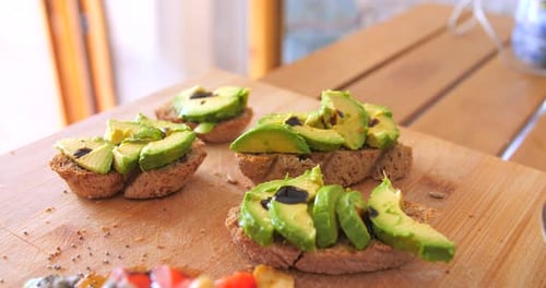 Close up view of nutritious breakfast toast of homemade bread along with pieces of green Avocado. Ve