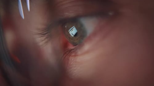 Plan rapproché de l'œil d'un homme qui regarde l'écran lumineux de l'ordinateur. Nomade numérique créatif concentré.