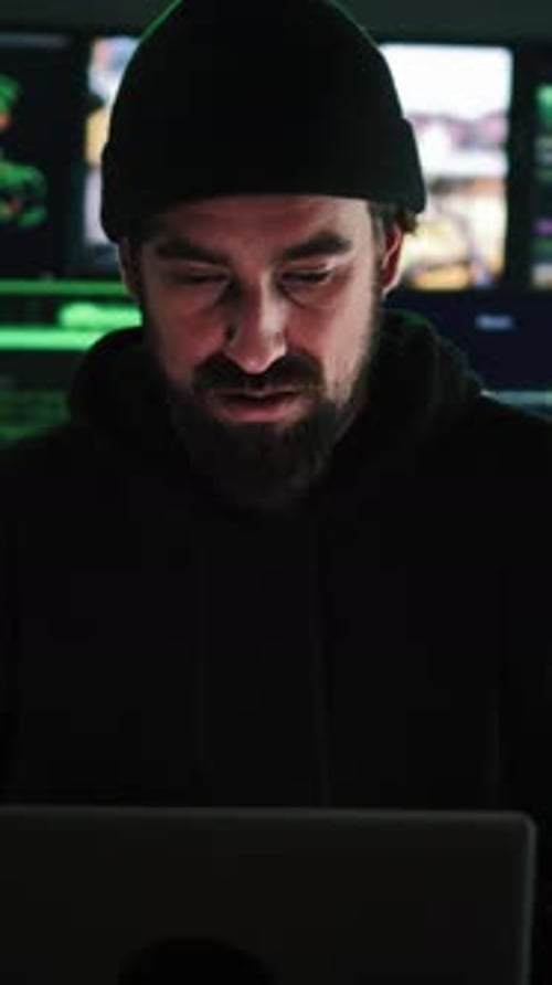 Vertical Close Up Portrait of a Criminal Hacker Man Programming a Phishing Virus at Background a Lot
