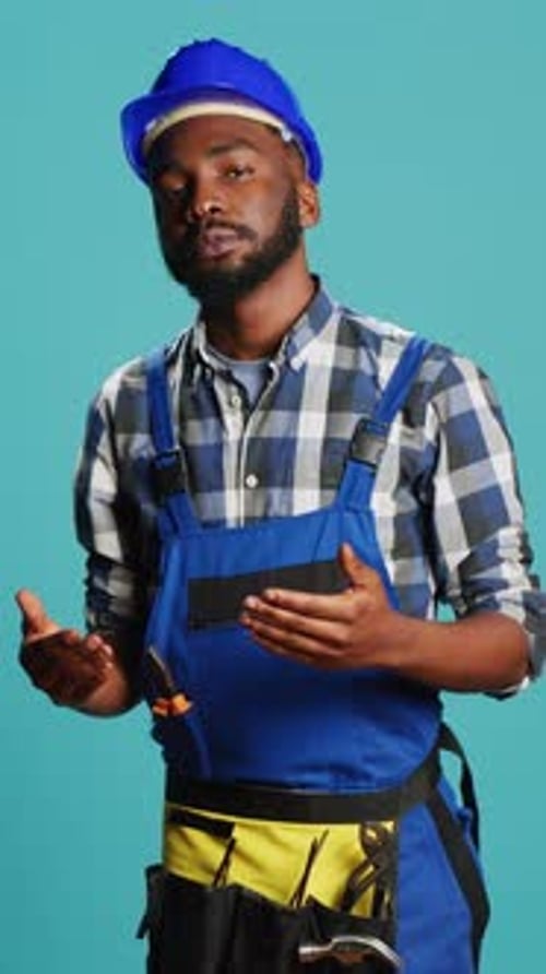 Man Wearing Construction Helmet Holding Smartphone and Screwdriver