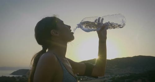 Woman Drinks Water After Coastal Exercise at Sunset