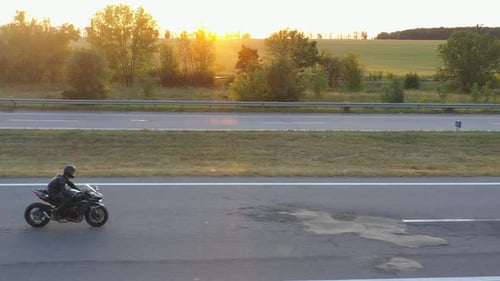 Aerial View to Biker Rides on Modern Sport Motorbike at Highway