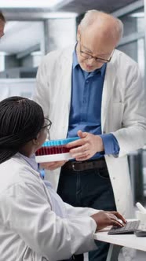 Vertical Video Scientists Team Handles Blood Samples in Test Tube Within Laboratory