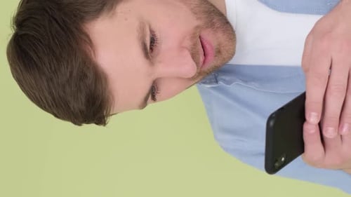 A Man with a Smartphone in His Hands Looks at the Screen of His Device He is Happy and Surprised