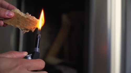 Starting a fire at the fire place with a long lighter.