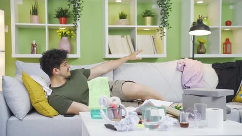Stressed Man Lying on Couch in Messy Living Room