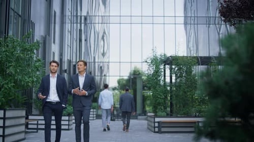 Two Successful Businessmen Walking at Modern Office Building Discussing Project. Focused Handsome