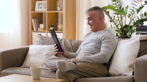 Man Relaxing on Sofa Using Tablet in Living Room