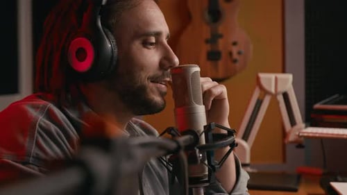 Smiling Young Man Speaking into Microphone on Live Podcast in Studio