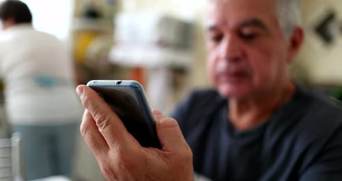 Older man using cellphone at home