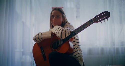 Young Woman With Guitar Smiling Indoors