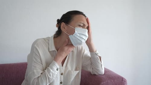 Woman with Headache and Face Mask Indoors