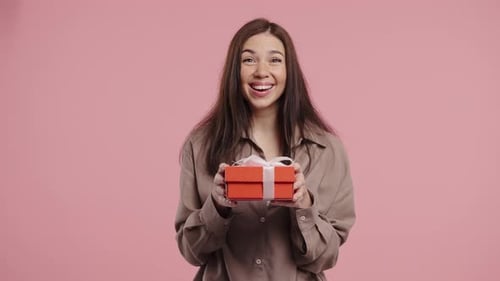 Excited Woman Holding Gift with Ribbon in Studio