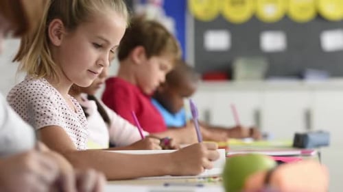 Children writing at desks in a classroom setting