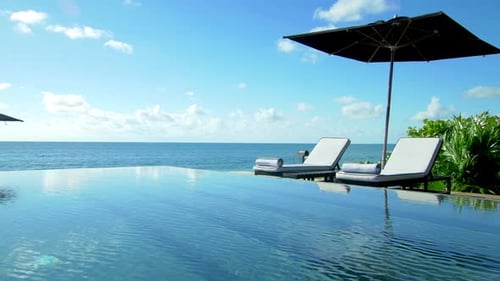 Tropischer Infinity-Pool mit Liegestühlen, Karibikblick und Strand