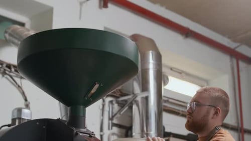 Factory Worker Pouring Coffee Grains in Roasting Machine