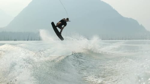 Front view of caucasian young man doing tricks on wakeboard in the city river 4k