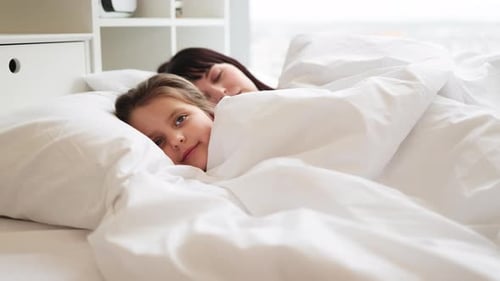 Mother and Daughter Resting Peacefully in Cozy Bed