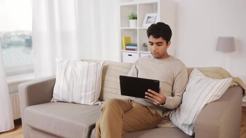 Young Man Relaxing on Sofa with Tablet
