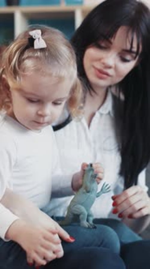 Woman and Child Play with Dinosaur Toy Indoors