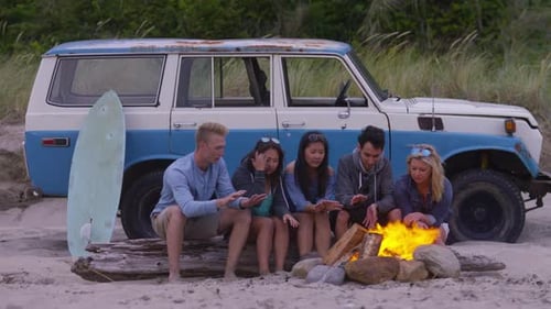 Young friends enjoying campfire fun on a carefree summer beach vacation