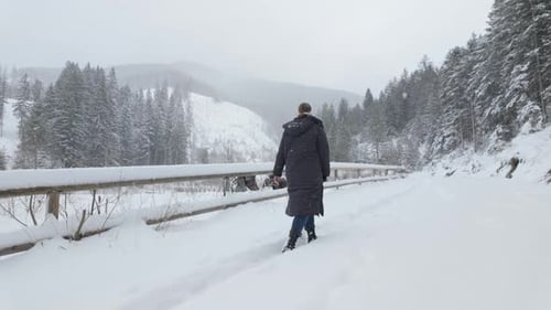 Person Walking To Snowy Path Along The Wooden Fence In Winter. - slow motion shot