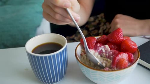 Person Eating Oatmeal and Strawberries for Breakfast