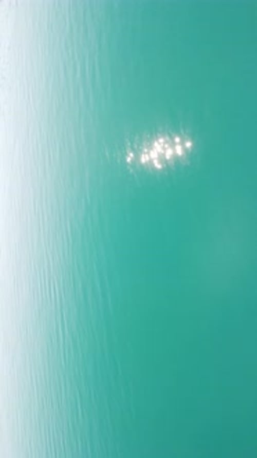 Vertical Aerial View on Sea Water Surface Camera Flies Over Clear Sea Water Sun Glare Abstract