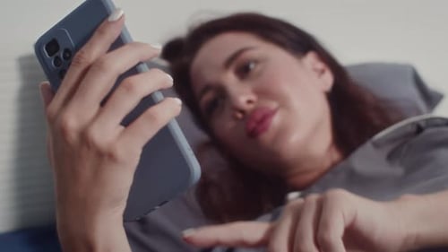 Woman Using Smartphone While Laying in Bed
