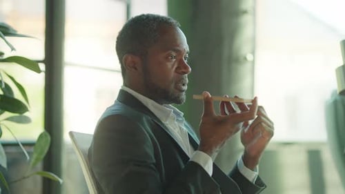 Adult Businessman Uses Smartphone in Urban Office