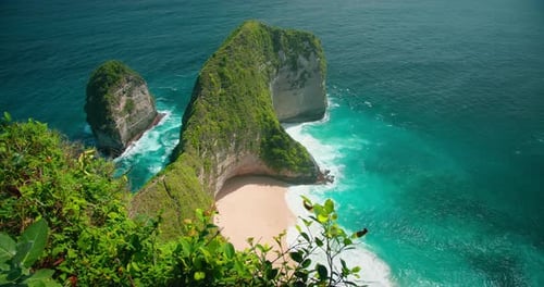 Blue Ocean Waves Crashing on Tropical Rocky Cliffs and Sandy Kelingking Beach Top Down View of