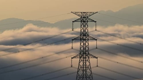 A high voltage tower and a sea of raging, tumbling clouds on a summer morning.
