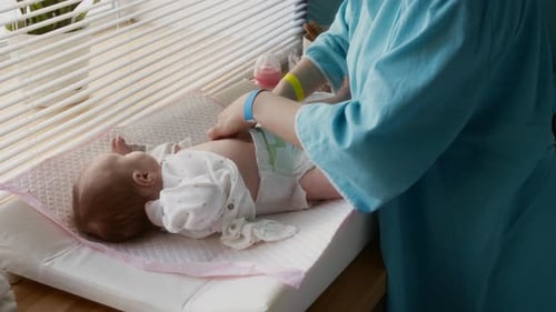 Nurse Changes Baby's Diaper on Changing Table