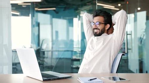 Man Celebrates Achievement Using Laptop in Modern Office